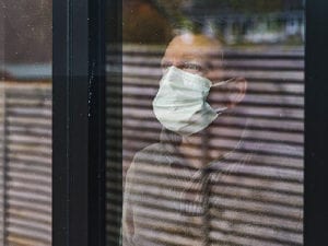 Man wearing mask looking out a window