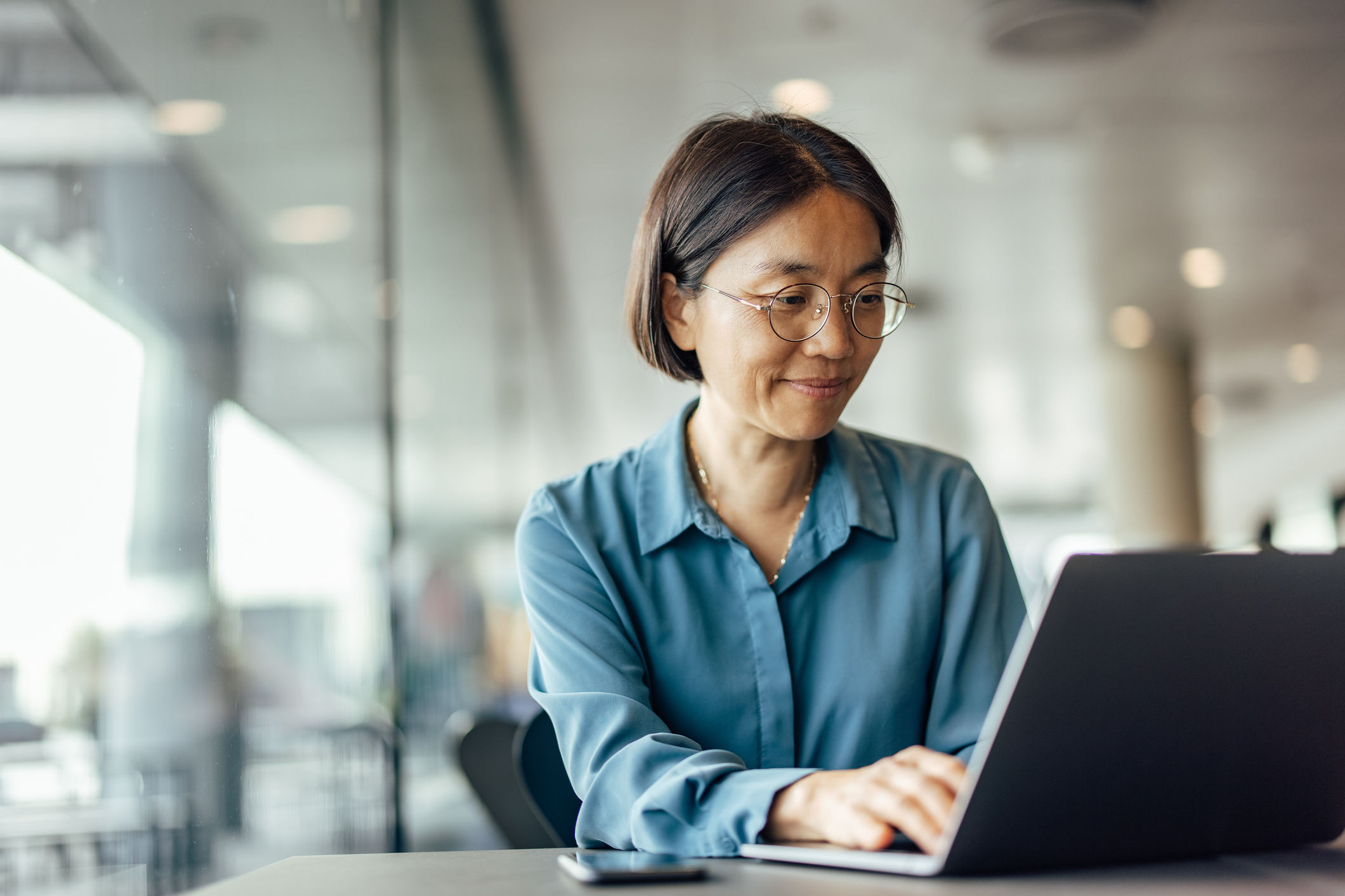 woman in blue shirt sitting at computer