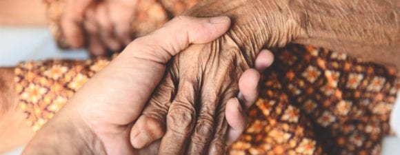 hospice patient and caregiver holding hands