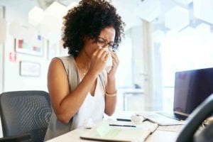 woman sneezing into a tissue