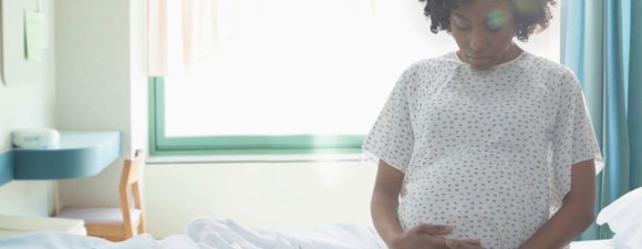 pregnant woman sits on hospital bed