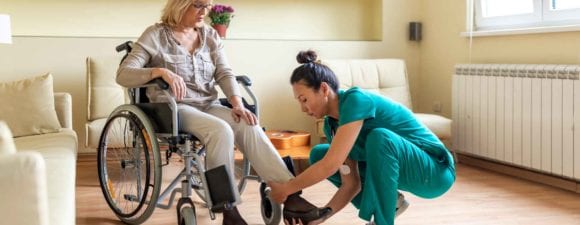 Nurse aide assisting resident in wheelchair