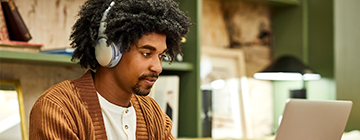 man studies at a computer with headphones