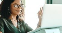 female with glasses and earpods at a laptop